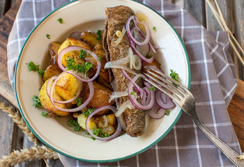 Fried herring and roasted potatoes on a old fashioned enamel plate