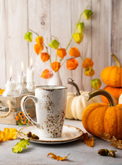 Autumn still life with cup of tea, pumpkins,flowers and candles on table.Thanksgiving day or...