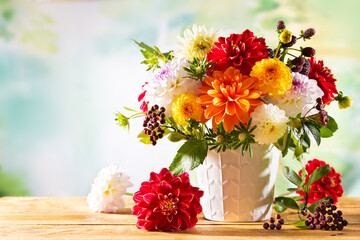 Autumn still life with garden flowers. Beautiful autumnal bouquet in vase on wooden table. Colorful dahlia, chrysanthemum and berries.