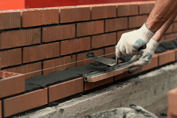 Mason trowels smears cement mortar on brick. Bricklaying when building house or stone fence.