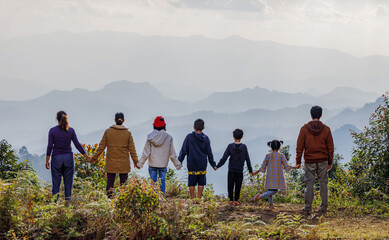 Fototapeta na wymiar Big family standing on hills looking at summer mountains landscape and sunset sky