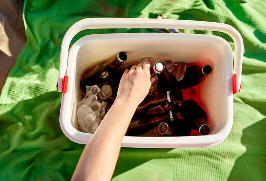 Crop woman taking beer from cooler