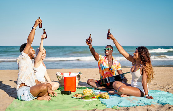 Diverse friends proposing toast on beach