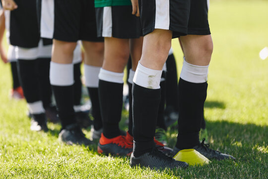 Sports team standing on grass venue. Closeup picture of soccer player's feet. Footballers standing in a row on training