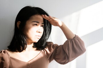 Asian woman covering her face and eye from sunlight worried to have skin sunburn because of...