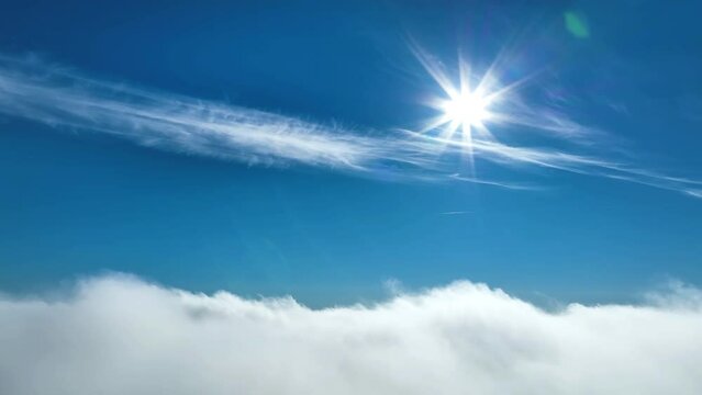 Aerial video above clouds with Sun, clear sky above fast moving white cloudscape