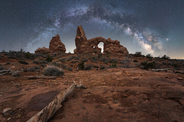 Steps leading to natural stone arch and canyon under starry sky with Milky Way