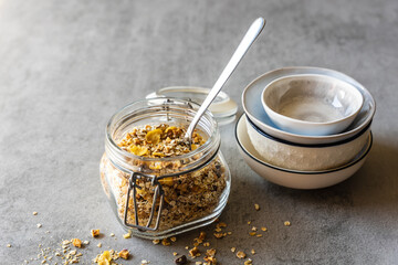 Frühstücksflocken in einem Vorratsglas und ein Stapel Schüsseln auf einem grauen Tisch. Nahaufnahme, Müsli.