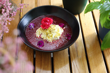 Dessert with forest fruit mousse, garnished with pistachio powder and flowers, selective focus.