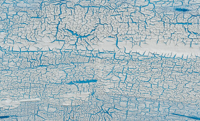 The texture of cracked paint. White texture with a craquelure effect on a blue background