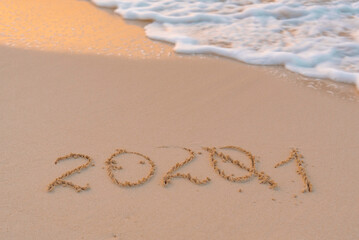handwritten inscription 2021 on the sand by the sea