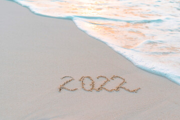 handwritten inscription 2022 on the sand by the sea on Maldives island
