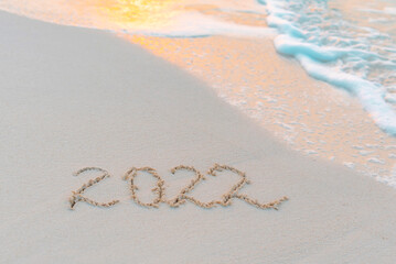 handwritten inscription 2022 on the sand by the sea on Maldives island