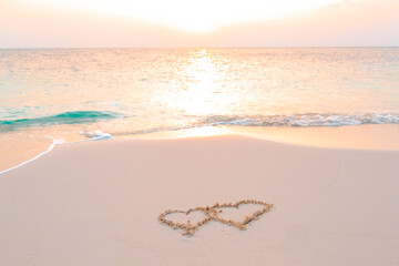 handwritten two heart on sand on Maldives island, concept of luxury travel and greetings for...