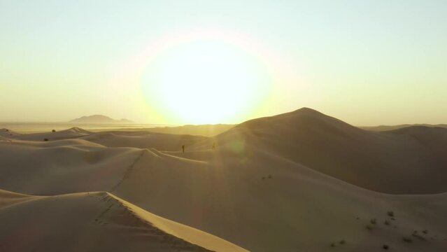 Beautiful desolate Sand Dune landscape as actors explore an early sunrise. Aerial drone footage sandy desert hills with sun rays. Shot on DJI Mavic 2 Pro. Imperial Sand Dunes, California United States