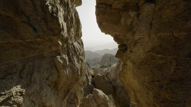 Hole in rock layered slate looking over canyon valley mountain range. Foggy southern cliffside perspective shot. Shot on 5k RED GEMINI. Mount Lemmon, Arizona United States