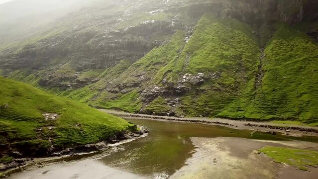 Aerial view of a lagoon and Saksun village, Faroe Islands. Beautiful green nature in Saksun. High quality 4k footage. Flying through a fjord in Faroe Islands.