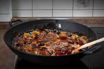 The process of boiling plum jam in a cast iron pan