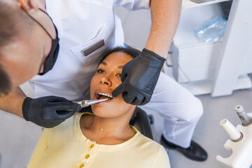 Calm woman sitting in dentist chair while doctor whitening her teeth