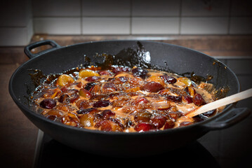 The process of boiling plum jam in a cast iron pan