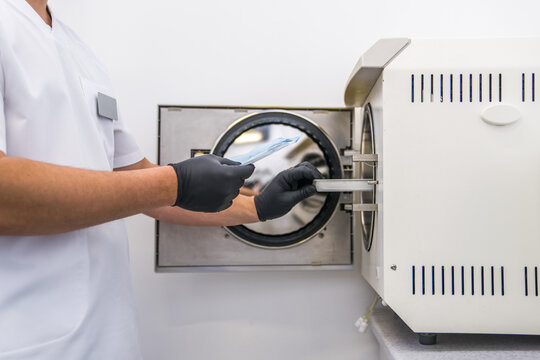 Dentist places medical autoclave for sterilising surgical and other instruments