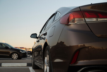 Fototapeta na wymiar Back view of a brown sedan car on a parking lot