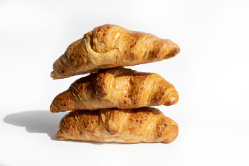 Fresh croissants in a stack on a white background. Homemade cakes, fresh bread from the bakery