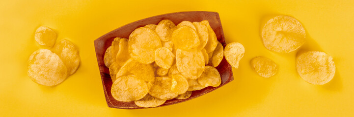Potato chips or crisps, a salty snack on a wooden background, a panorama, overhead flat lay shot