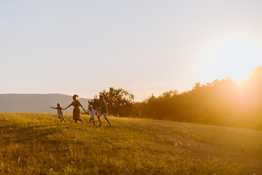 Happy Young Family Spending Time Together Outside In Green Nature.