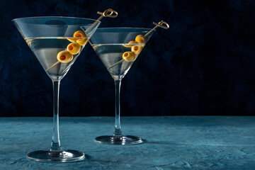 Martini, two glasses with spicy olives, on a dark blue background. Alcoholic drinks with a place...