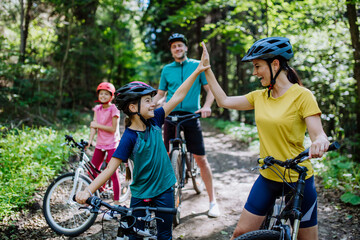Young family with little children preapring for bike ride, standing with bicycles in nature and...