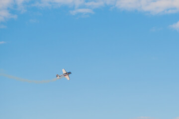 Small retro airplane, light aircraft flying in blue sky and doing stunts at Air Show. Performance, extreme, aerobatic and sport concept