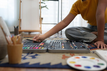 Joyful young female artist choosing colour pencil at workshop