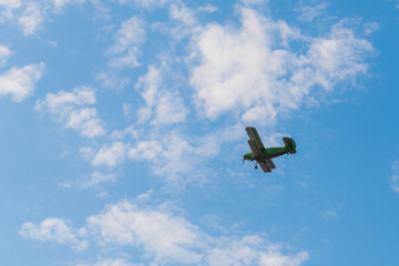 Green biplane, retro airplane flying in blue sky at Air Show. Performance, extreme, aerobatic, sport and aircraft concept