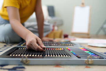 Joyful young female artist choosing colour pencil at workshop