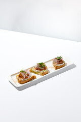 Aesthetic composition with tomato bruschetta on white background with harsh shadows. Italian bruschetta with tomatoes and cheese on fine dining in summer. Elegant menu concept.