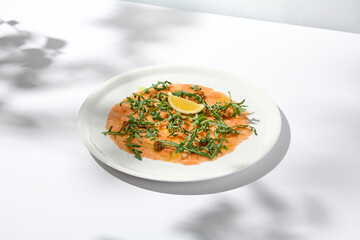 Salmon carpaccio with arugula on white background in summer day. Fish appetizer - salmon carpaccio...