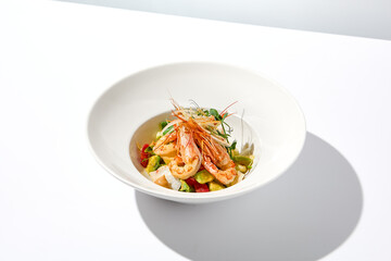 Elegant food - salad with shrimp and avocado on white table with harsh shadow. Flashy food concept....