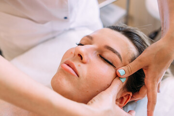 Fototapeta na wymiar Cosmetologist does facial massage for woman. Beauty skin care