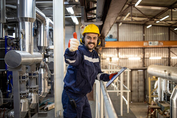 Portrait of petroleum refinery foreman working night shit and holding thumbs up.