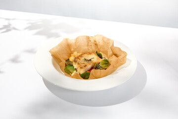 Baked cod fillet with vegetables in parchment. Roasted cod steak with cauliflower. Healthy food in summer menu. White fish roasted in parchment. Fish dish in white background with shadows.