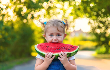 Child girl eats watermelon in summer. Selective focus.