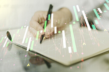 Double exposure of abstract creative financial chart with hand writing in notebook on background, research and strategy concept