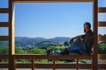 Handyman resting and having break when working on wooden construction site, diy eco-friendly homes...