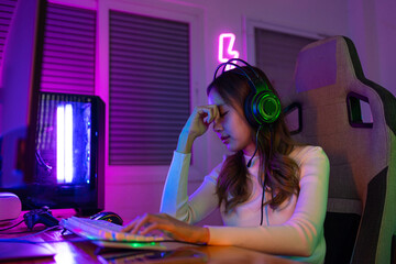 Eyes tired. Gamer and E-Sport online of Asian woman playing online computer video game with lighting effect, broadcast streaming live. Her eyes were tired from staring at the screen for a long time.