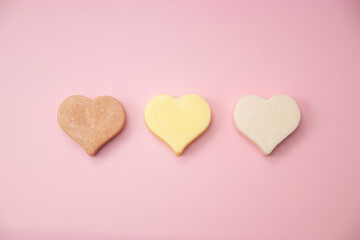 Heart shaped pink bar of soap on a light pink background. Top view, copy space. Heart shaped soaps. Importance of personal hygiene care. Copy space.