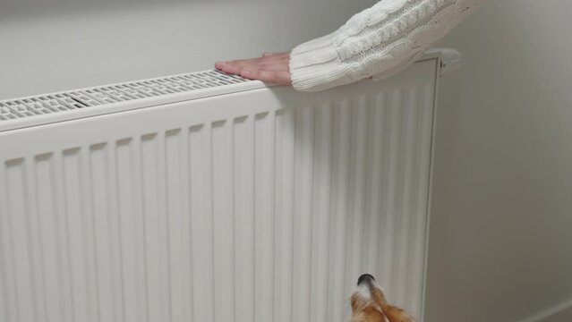 Woman adjusting temperature on heating radiator, Energy crisis concept in Europe, Rising costs in private households for gas bill due to inflation and war