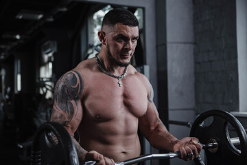 Fototapeta na wymiar Big muscular male bodybuilder lifting barbell, exercising shirtless at gym