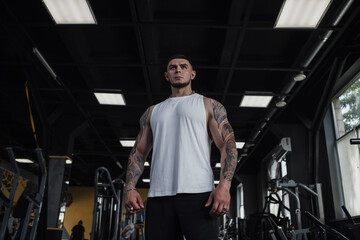 Fototapeta na wymiar Low angle portrait of a strong confident muscular athlete standing confidently at the gym