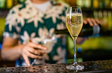Bartender pouring champagne into glass in bar